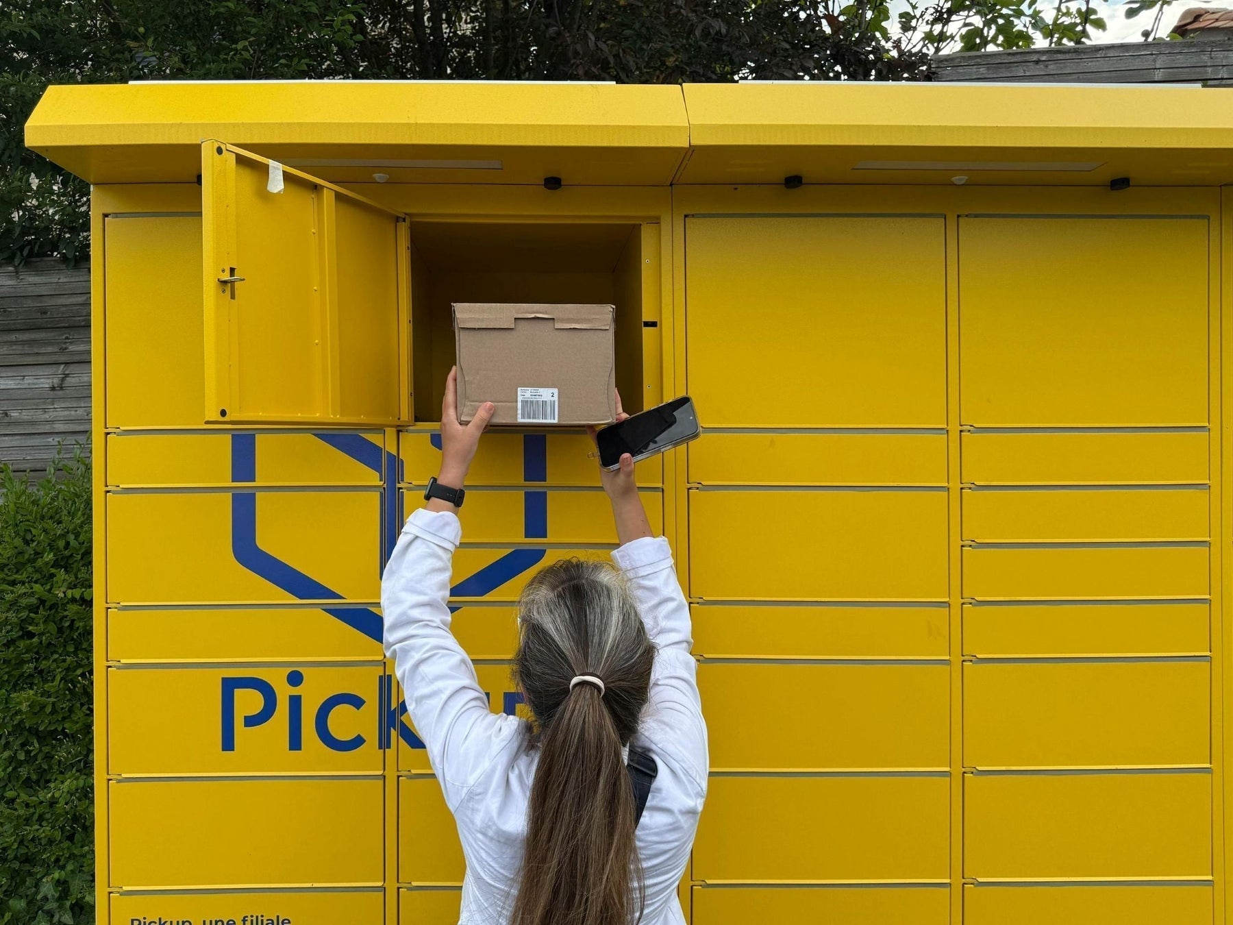 Customer inserting a parcel into a yellow parcel locker – illustrating parcel locker box sizes.