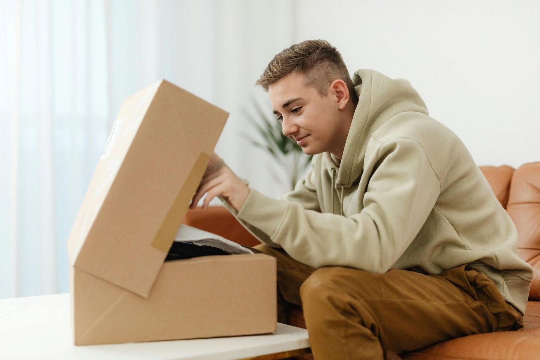 Young man unboxing a parcel at home — illustrating customer experience with e-commerce packaging.