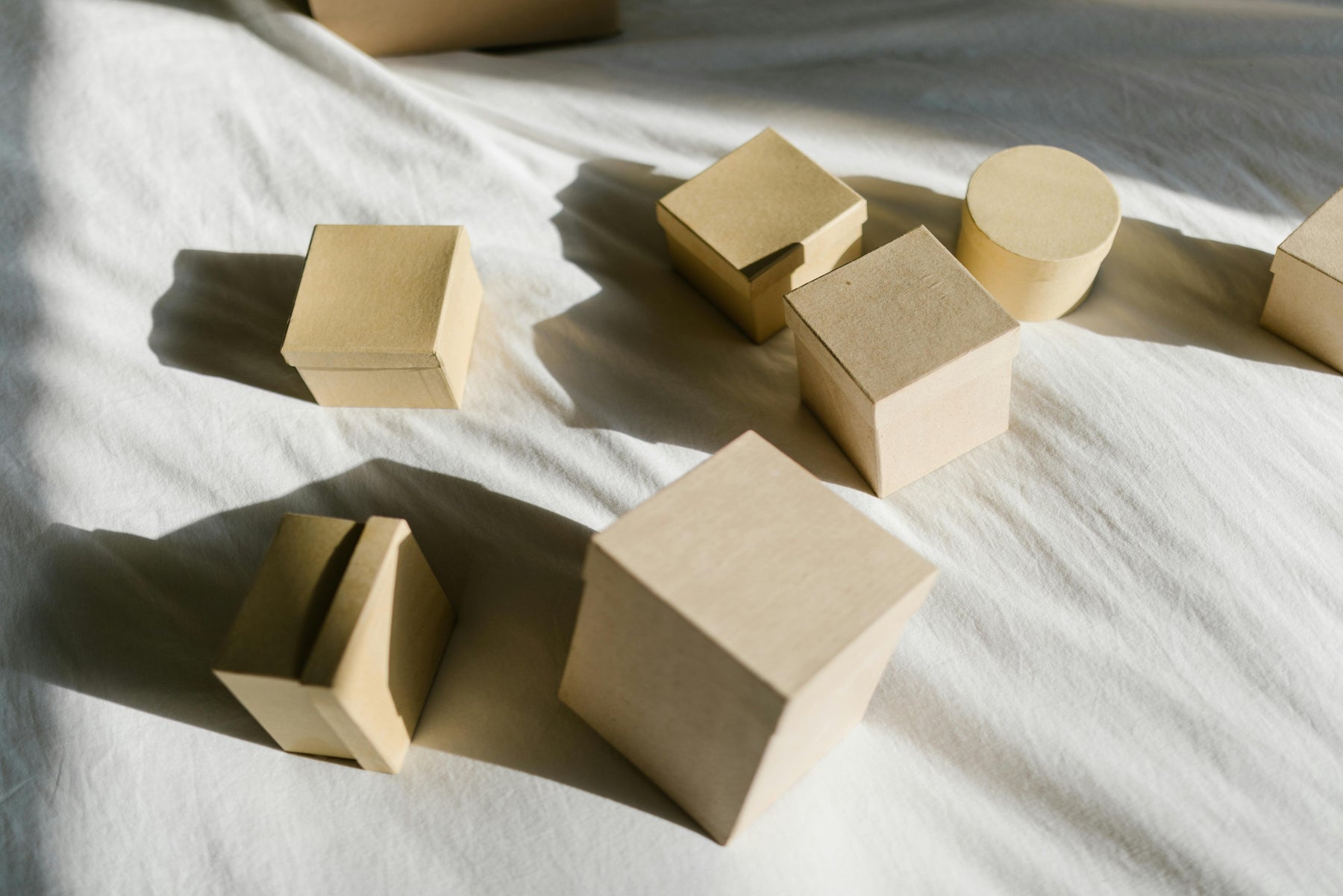 Cardboard boxes of different shapes on a white surface, representing eco-friendly and sustainable packaging alternatives.