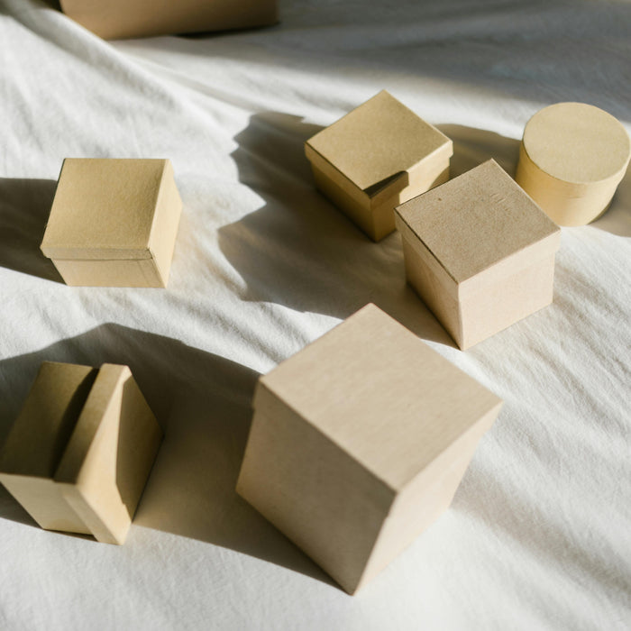 Cardboard boxes of different shapes on a white surface, representing eco-friendly and sustainable packaging alternatives.